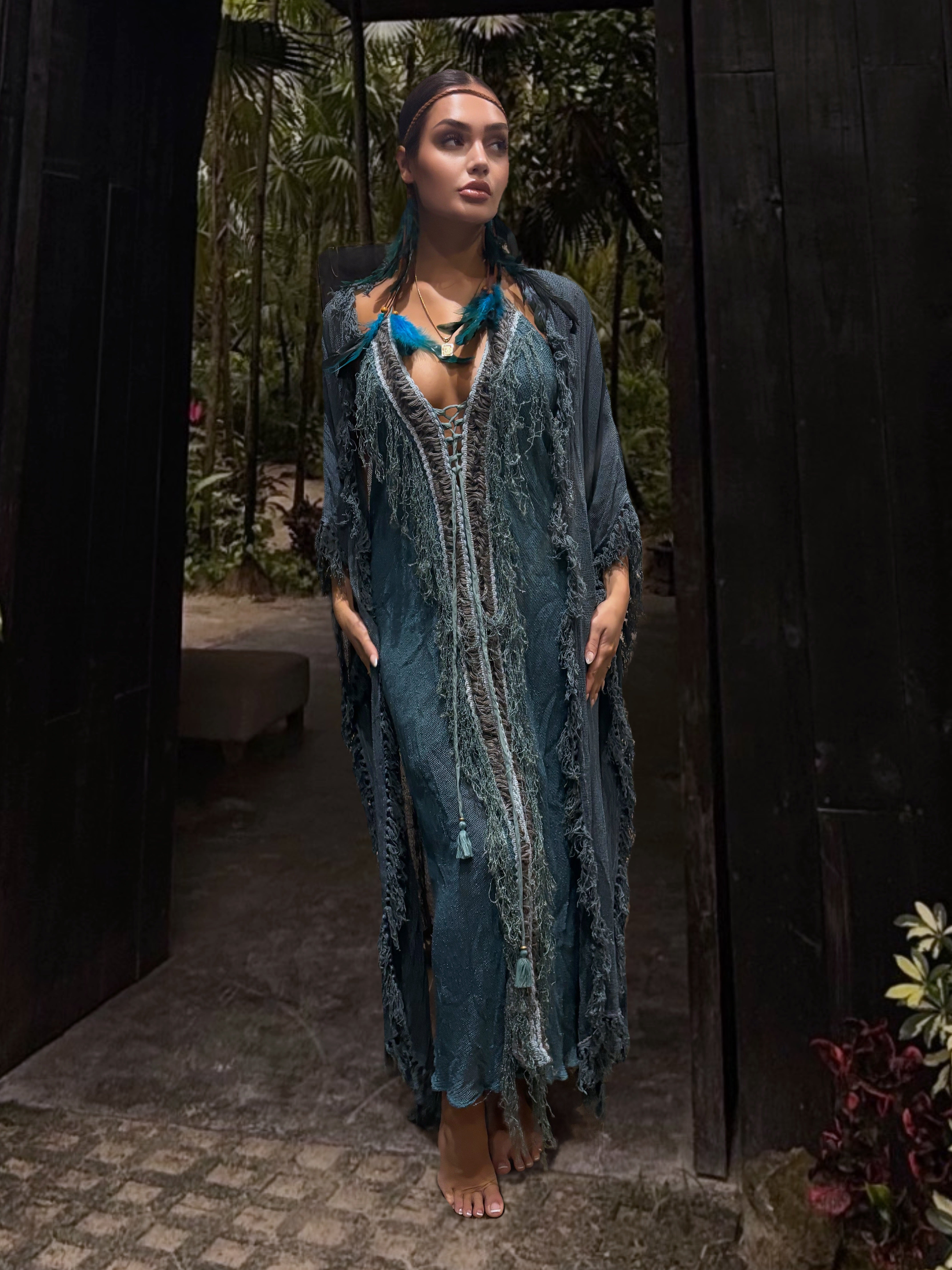 A woman wearing a sleeveless, textured mesh cotton maxi dress in blue and green colors with a matching hand dyed robe, standing in a tropical setting.